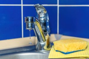 Kitchen faucet with water dripping out while faucet if off.