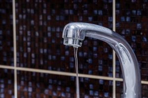 Water slowly leaking out of a faucet.
