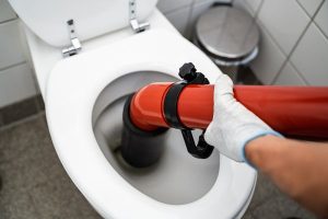 Plumber fixing a toilet with a piece of heavy equipment.